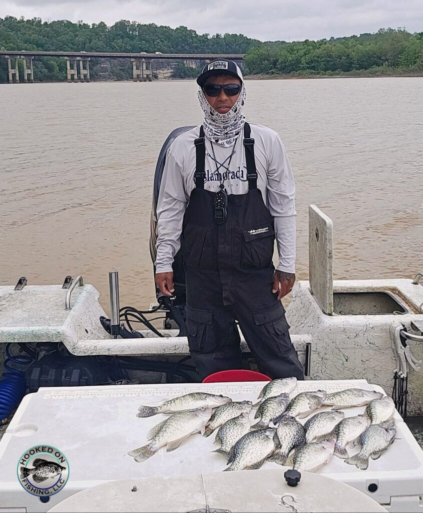 Juan from Hooked on Fishing standing in his boat on a lake with a collection of fish caught