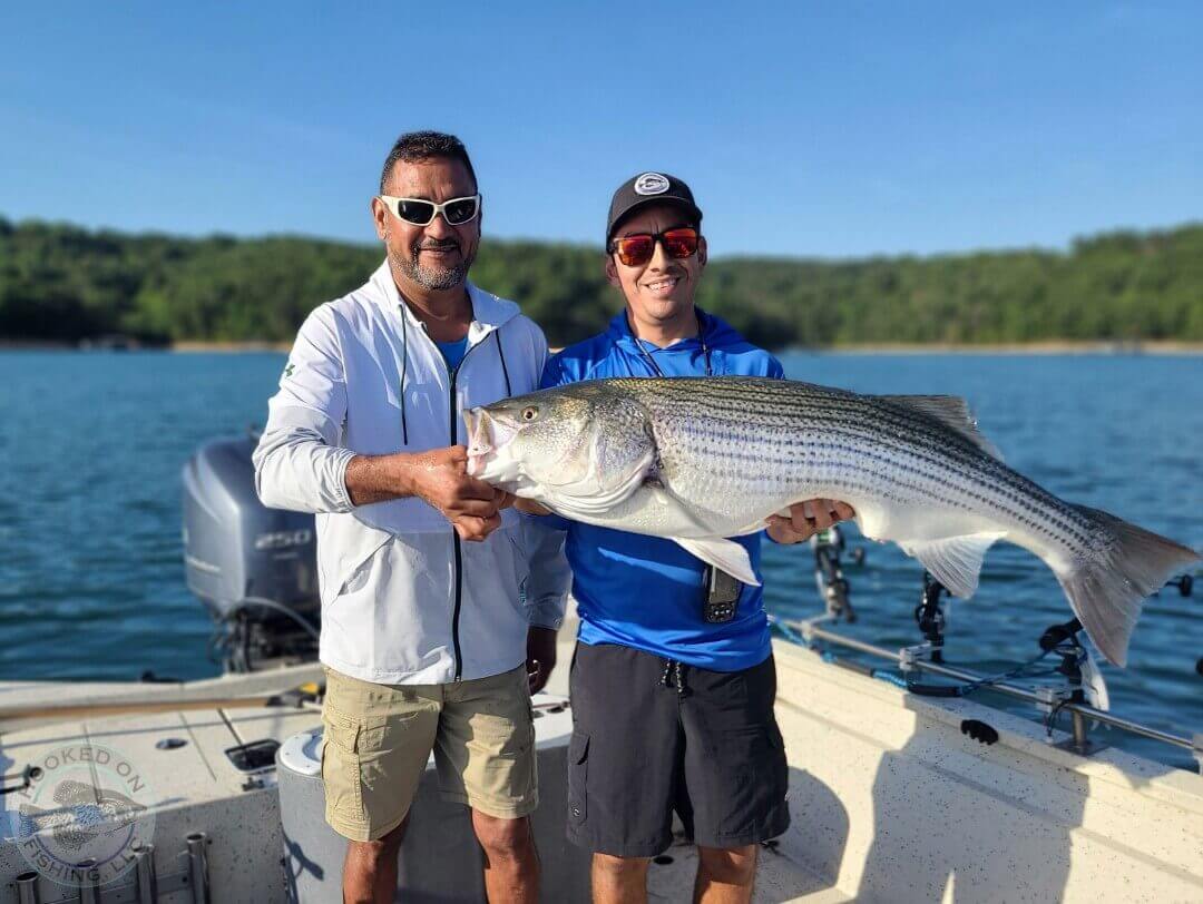 two men on a fishing boat holding their catch of the day while on Beaver Lake